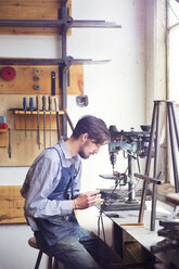 Männlicher Handwerker bei der Arbeit an Maschinen in einer Holzwerkstatt - CAVF27847