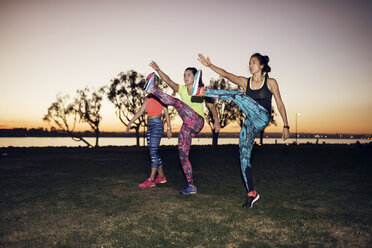 Sportlerinnen trainieren auf dem Feld gegen den klaren Himmel im Park bei Sonnenuntergang - CAVF27901