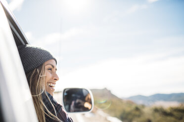 Smiling young woman riding in car against sky - CAVF27905