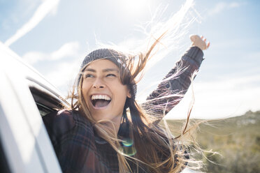 Cheerful young woman enjoying in car against sky - CAVF27906