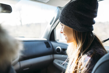 Lächelnde junge Frau im Auto sitzend während einer Autoreise - CAVF27908