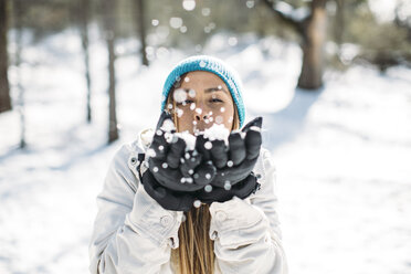 Frontansicht einer Frau, die auf einem Feld stehend Schnee bläst - CAVF27911