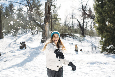 Front view of cheerful woman playing with snow in field - CAVF27912