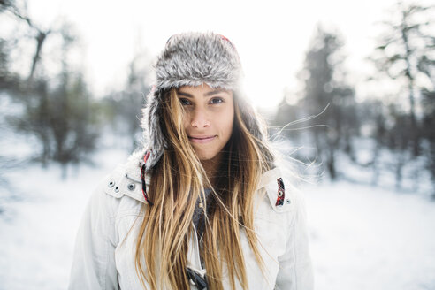 Porträt einer lächelnden Frau mit Pelzmütze auf einem verschneiten Feld - CAVF27918