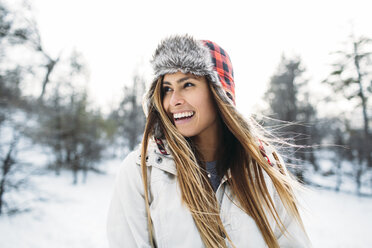 Nahaufnahme einer fröhlichen Frau mit Pelzmütze auf einem schneebedeckten Feld - CAVF27920