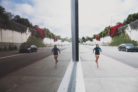 Sportlerin läuft auf dem Fußweg neben einem Glasgebäude, lizenzfreies Stockfoto