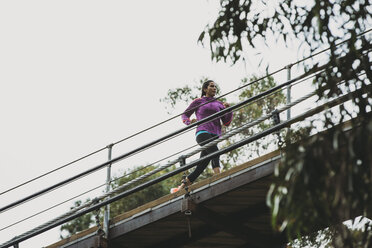 Niedriger Winkel Ansicht der Sportlerin joggen auf Fußgängerbrücke gegen den Himmel - CAVF27944