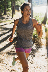 Frau joggt auf einem Feld an einem sonnigen Tag - CAVF27947