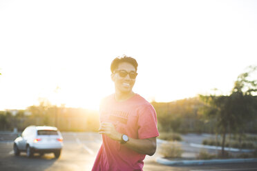 Mann mit Sonnenbrille steht auf einem Parkplatz gegen den klaren Himmel bei Sonnenuntergang - CAVF27961