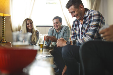 Lächelnde Freunde beim Kartenspiel während eines geselligen Beisammenseins zu Hause - CAVF27978