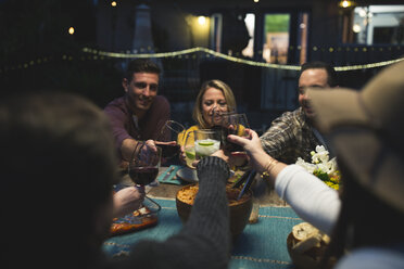 Friends toasting wineglasses while sitting at table during dinner party - CAVF28010