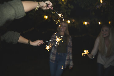 Female friends enjoying with sparklers at night - CAVF28023