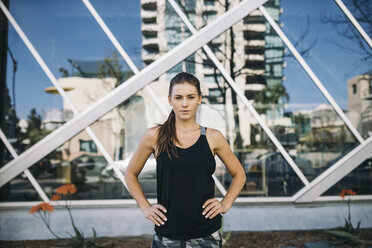 Portrait of confident female athlete standing with hands on hip in city - CAVF28051