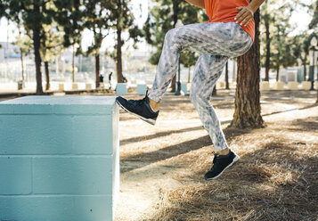 Low section of female athlete jumping on small blue column at park - CAVF28055