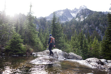 Hiker and dog walking on rocks by Snow Lake against mountains - CAVF28115