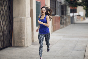 Determined sportswoman running on sidewalk - CAVF28135