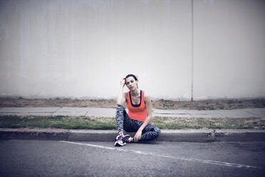 Porträt einer müden Sportlerin auf dem Bürgersteig sitzend - CAVF28143