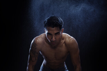 Portrait of confident muscular build kickboxer against black background - CAVF28151