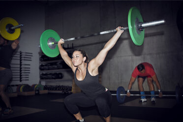 Entschlossene Sportlerin hebt Langhantel im Fitnessstudio - CAVF28163