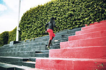 Rear view of sportswoman running on steps in stadium - CAVF28175