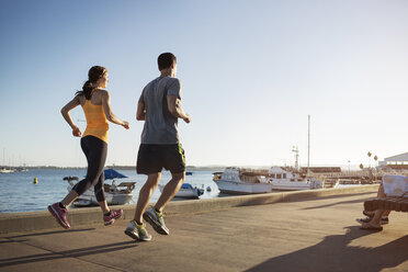 Rückansicht von männlichen und weiblichen Sportlern beim Joggen auf dem Pier am Hafen - CAVF28202