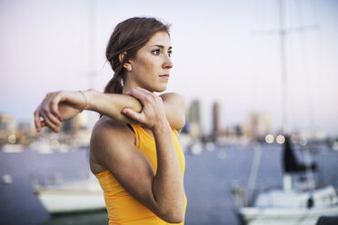 Entschlossener weiblicher Athlet streckt Arm durch Hafen gegen klaren Himmel - CAVF28221