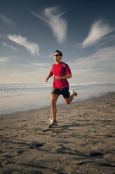 Entschlossener Sportler in voller Länge beim Laufen am Strand - CAVF28235