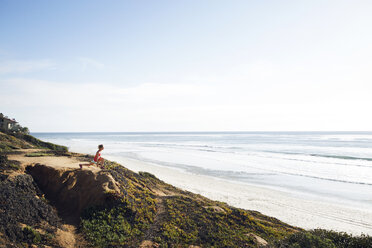 Mid distance of sporty woman exercising on rock at beach - CAVF28245