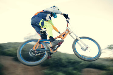 Low angle view of mountain biker performing stunt against clear sky - CAVF28251