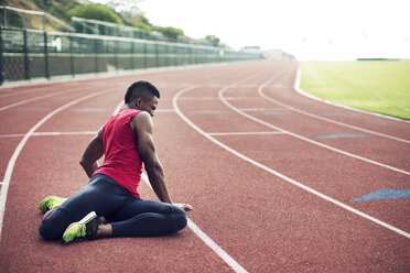 Full length of male athlete exercising on running tracks - CAVF28263