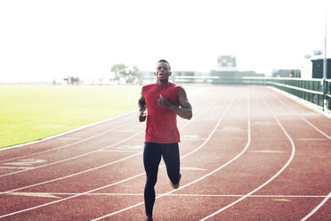 Determined male athlete running on field against clear sky - CAVF28268