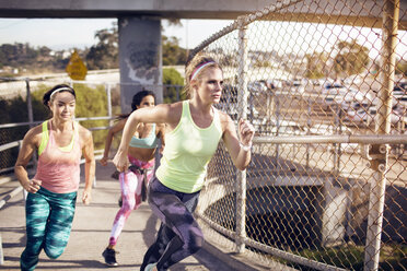 Entschlossener Sportler joggt auf einer Brücke in der Stadt - CAVF28292