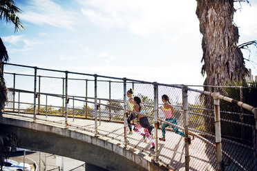 Seitenansicht einer Joggerin auf einer Brücke gegen den Himmel - CAVF28294