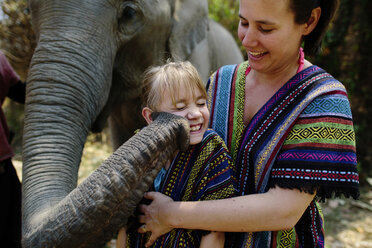 Elefant, der ein Mädchen mit dem Rüssel berührt, das bei seiner Mutter steht - CAVF28310