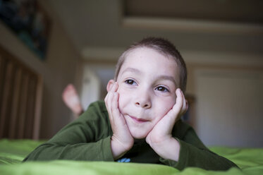 Close-up of thoughtful boy lying on bed at home - CAVF28337