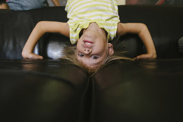 Porträt eines Mädchens kopfüber auf dem Sofa zu Hause - CAVF28352