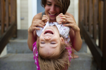 Glückliche Mutter spielt mit ihrer Tochter, während sie auf den Stufen sitzt - CAVF28355