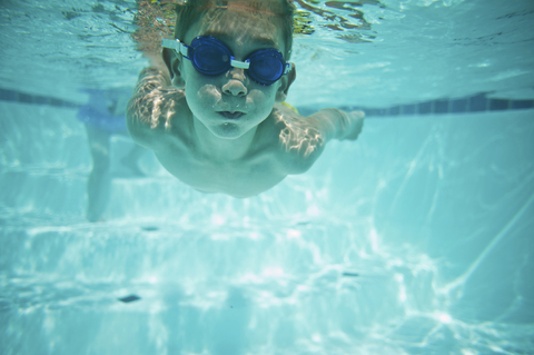 Hemdloser Junge schwimmt unter Wasser im Pool, lizenzfreies Stockfoto