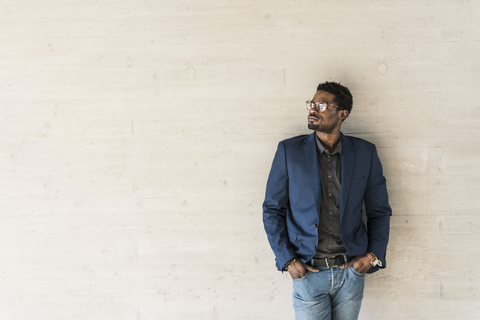 Businessman standing at concrete wall looking away stock photo