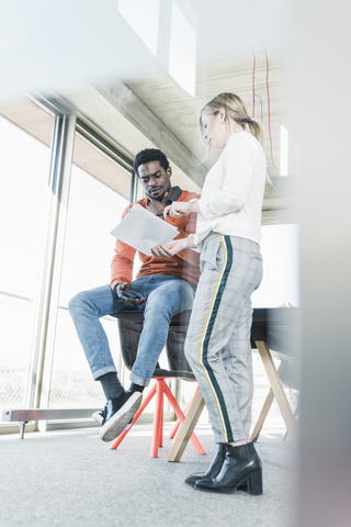 Casual businesswoman and businessman discussing papers in office stock photo