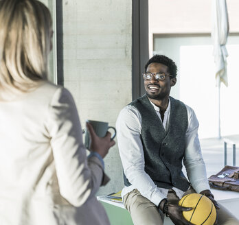 Geschäftsmann mit Basketball im Büro lächelt einen Kollegen an - UUF13120