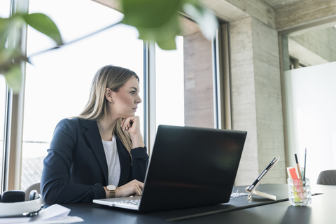 Junge Geschäftsfrau arbeitet mit Laptop am Schreibtisch im Büro, lizenzfreies Stockfoto