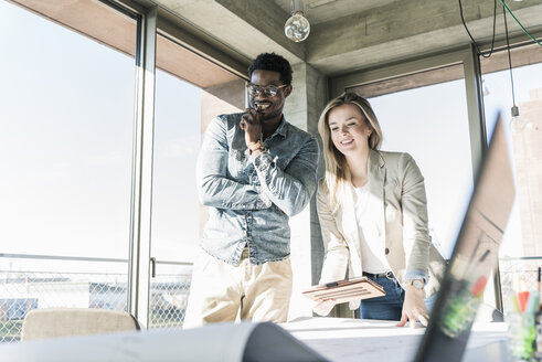 Two colleagues working on plan at table in office - UUF13166