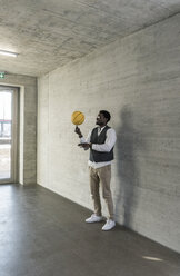 Businessman balancing basketball on office floor - UUF13169