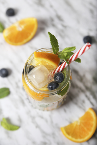 Glass of infused water with orange, blueberries and mint on ice stock photo