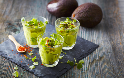 Glasses of avocado cream with chili flakes, cress and parsley stock photo