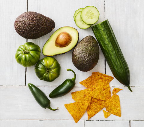 Geschnittene und ganze Avocado, grüne Tomaten, Jalapeno-Paprika, Gurke und Tortilla-Chips, lizenzfreies Stockfoto