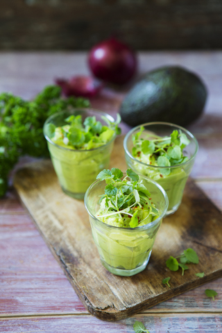 Glasses of avocado cream with chili flakes, cress and parsley stock photo