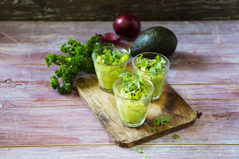 Glasses of avocado cream with chili flakes, cress and parsley - KSWF01860