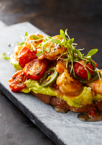 Crostini mit Garnelen und Tomaten, geröstetes Brot, Kräuter, Avocadocreme, süße Chilisauce, Jalapenos, Kresse, lizenzfreies Stockfoto